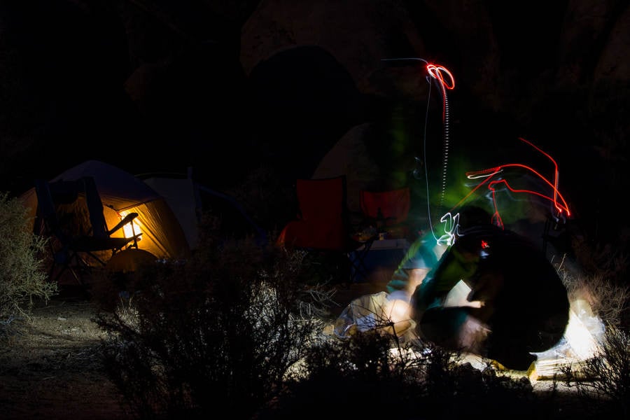 Night Shot of a Hiker at a Camp with Multiple Light Trails from the Headlamp