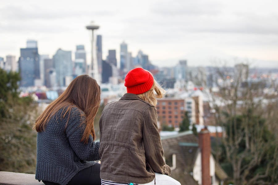 Two Girls Sitting in a Park with Seattle Cityline in the Background