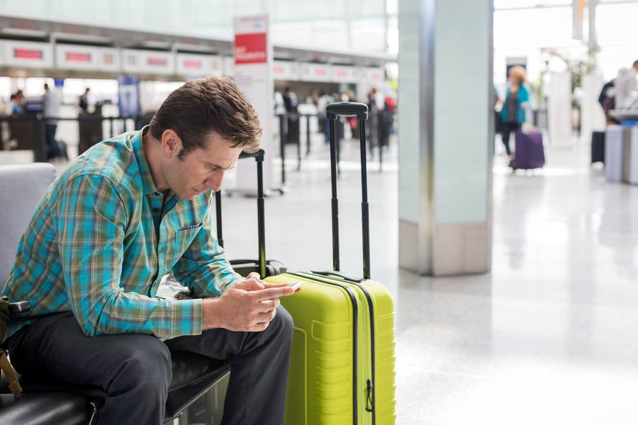 Traveler Sitting at an Airport Lobby Looking at a Cell Phone
