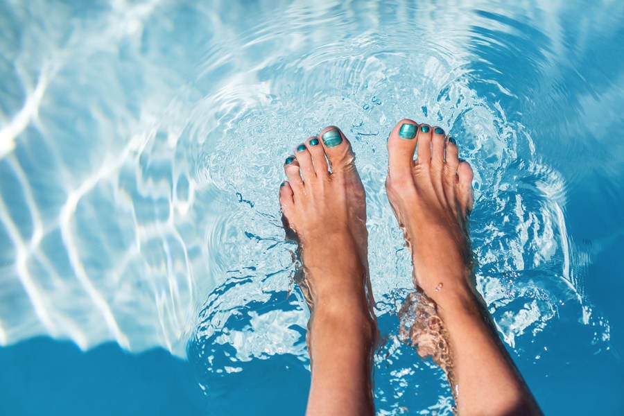 Close-Up of a Woman Dipping Her Bare Feet in a Turquoise Pool