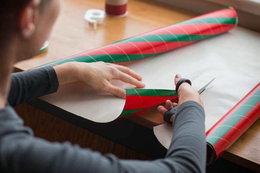 Woman Cutting Christmas Paper on a Table