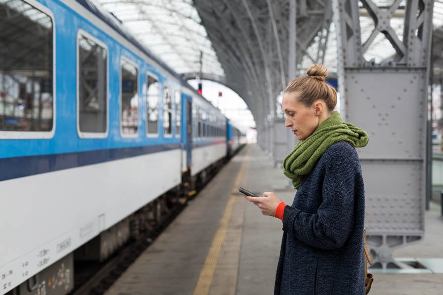 Woman with a Cell Phone on a Train Station Platform