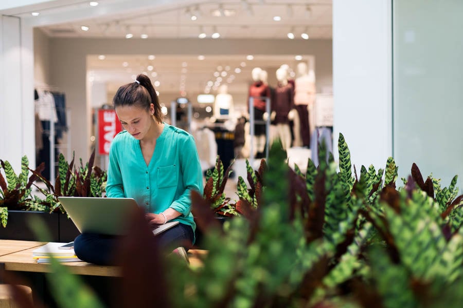 Young Woman Working on a Laptop in a Shopping Mall
