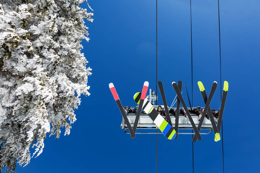 Straight-Up View of Skiers and a Snowboarder on a Ski Lift