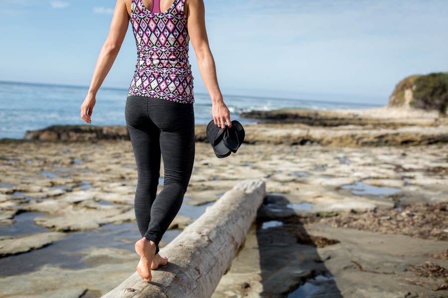 Carefree Athletic Woman Walking on a Tree Trunk on a Beach