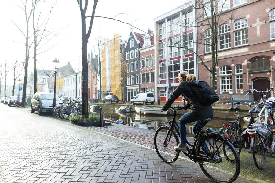 Woman Riding a Bicycle by a Canal in Amsterdam