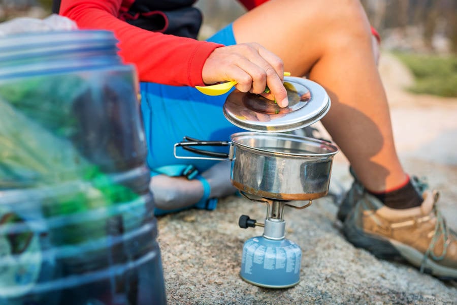 Outdoorsy Girl on a Backpacking Trip Cooking on a Stove