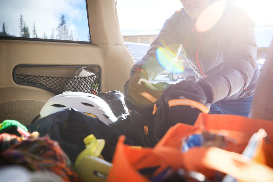 Woman Reaching for Snowboarding Gear in the Trunk of an SUV