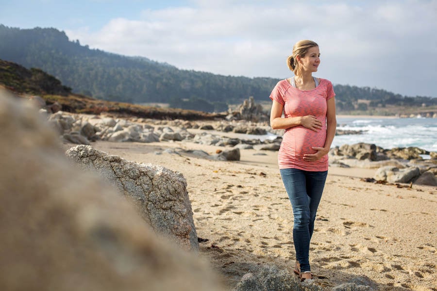 Smiling Pregnant Woman Walking on a Beach