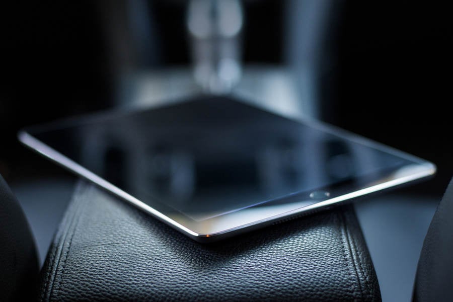Black Tablet Lying on a Leather Armrest Inside a Car