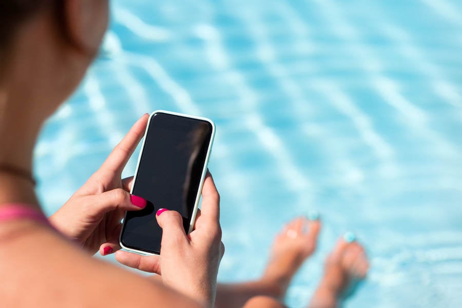 Close-Up of a Woman Sitting by Pool and Browsing on a Smartphone