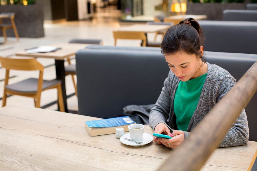 Girl Using a Smartphone in a Shopping Mall Cafe