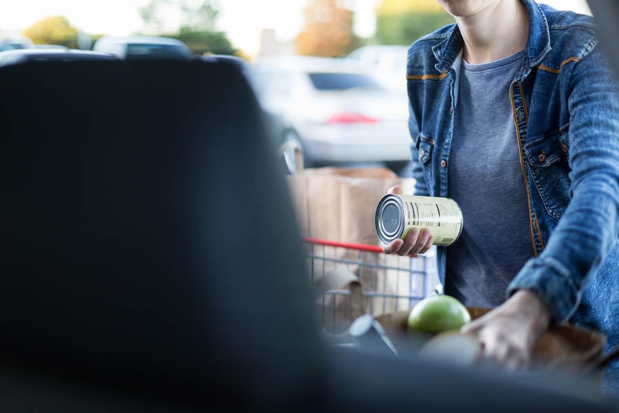 Woman Organizing a Bag of Groceries in a Trunk of a Car