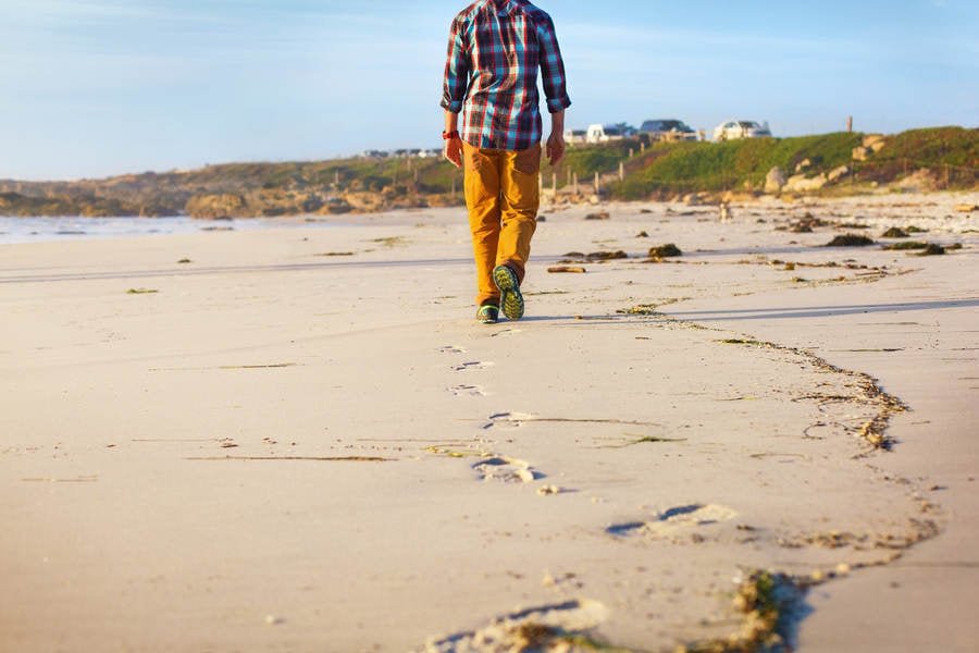 Low-Angle View of a Man Walking on the Beach Leaving Footprints Behind