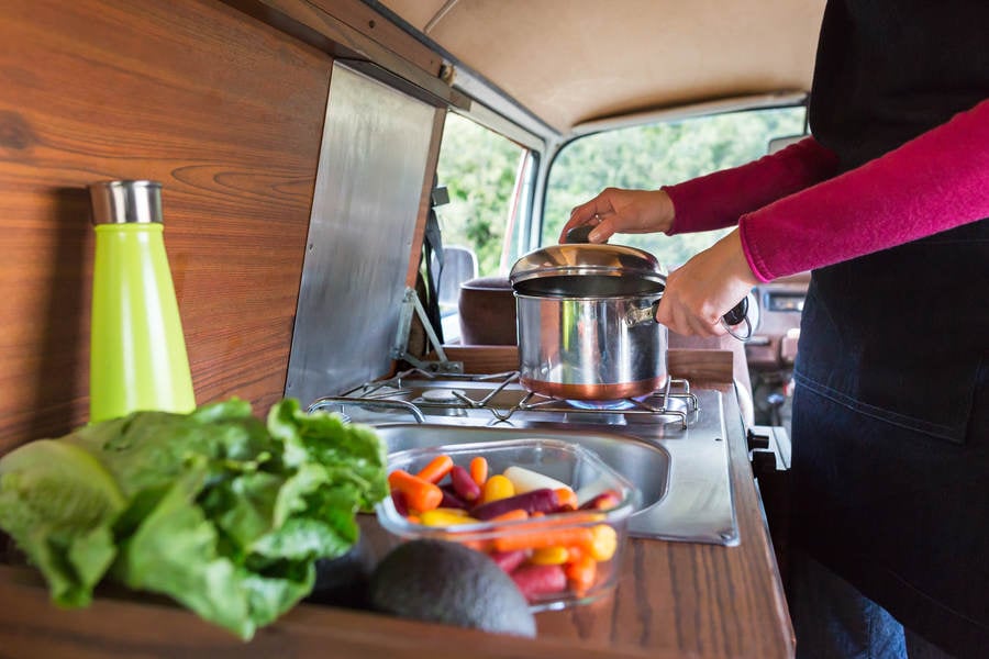 Young Woman Cooking a Meal in a Camper Van