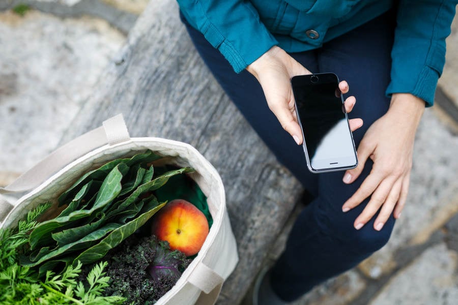 Woman with a Shopping Bag with Fresh Produce Holding a Smartphone