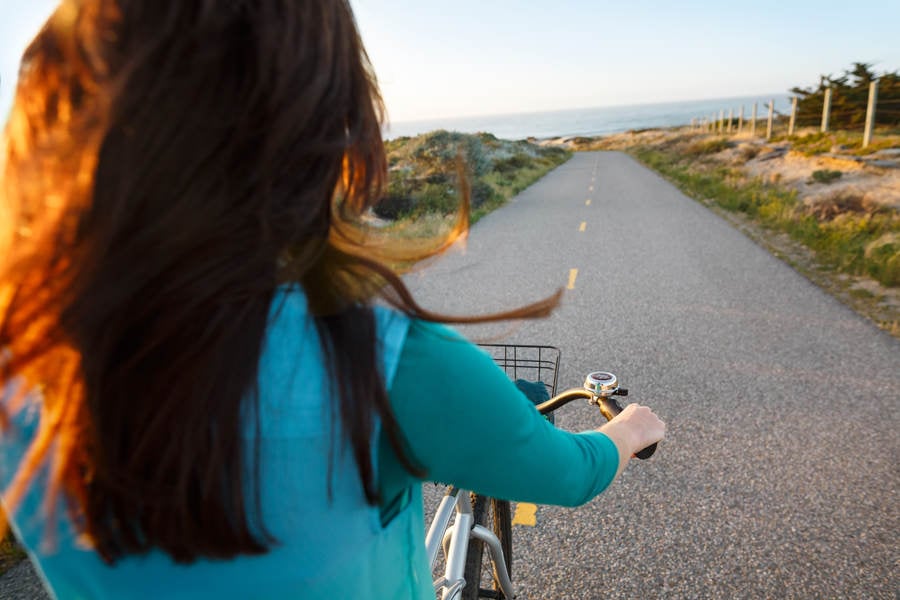 Rear View of a Woman Riding a Cruiser Bike on a Bike Path