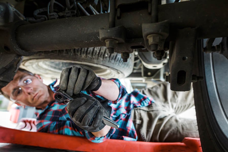 Car Mechanic Putting Socket on a Wrench Underneath a Truck