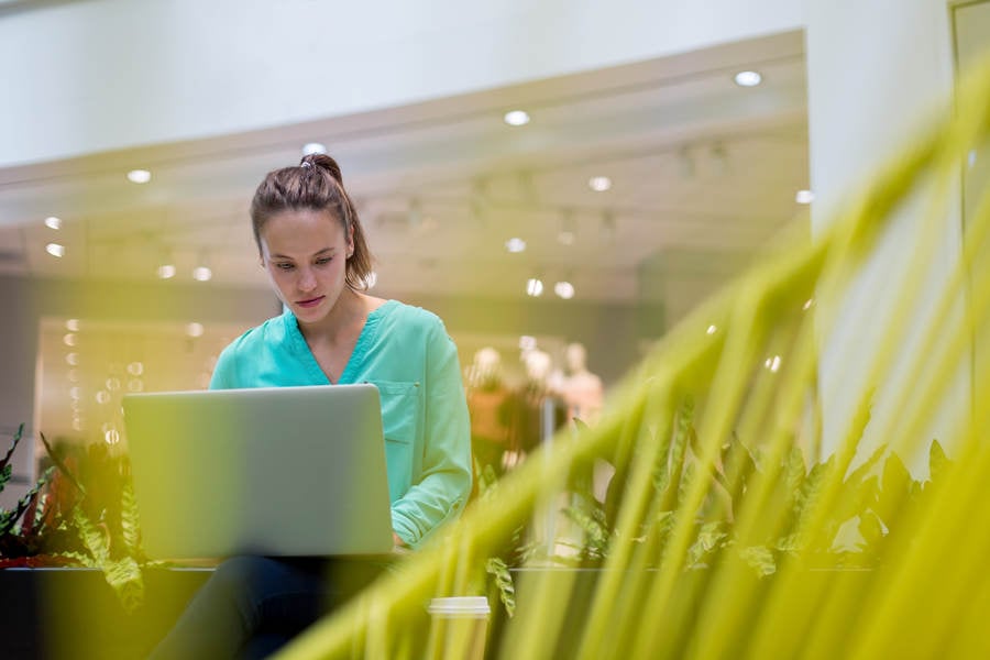 Woman in Casual Clothing Working on a Laptop in a Shopping Mall