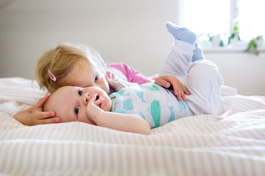 Little Girl Laying Next to Her Younger Brother in a Bed