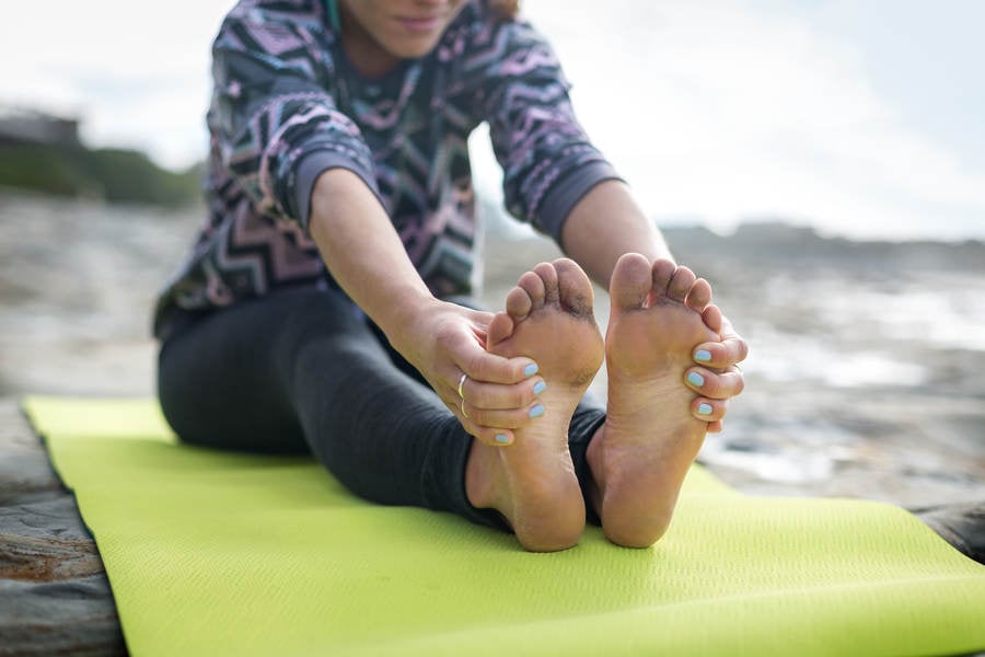 Young Athletic Woman Stretching on a Yoga Mat on a Beach