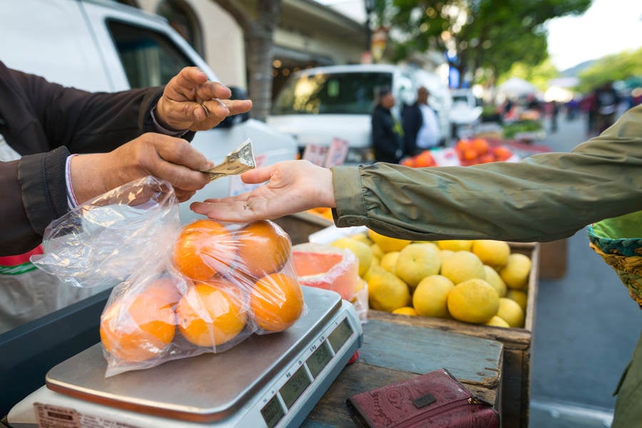 Woman Paying for Fresh Oranges at a Farmers Market