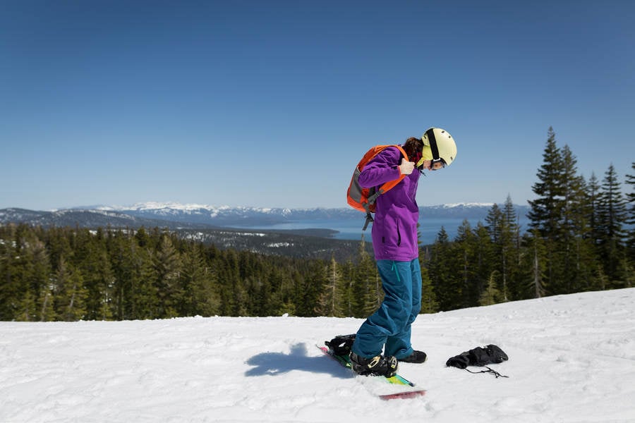 Female Snowboarder with a Backpack on a Top of a Ski Run