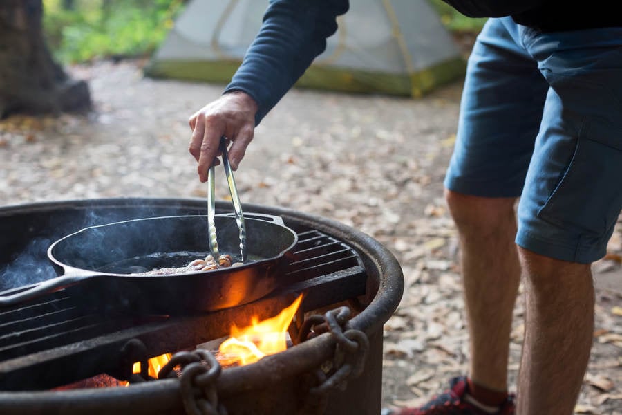 Man Using Tongs While Cooking Breakfast in a Campground