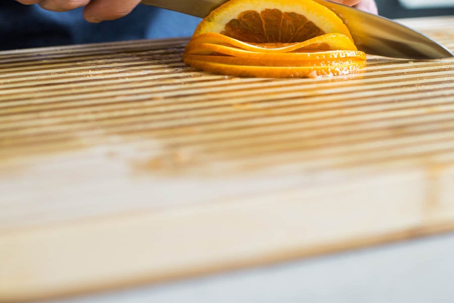 Man Slicing an Orange on a Cutting Board in a Kitchen