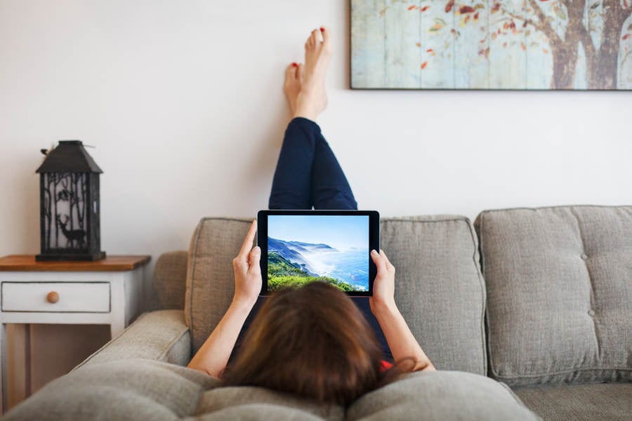 Woman Relaxing on a Sofa Looking at a Digital Tablet