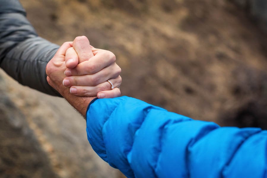 Outdoorsy Man and a Woman in Down Jackets Clasping Hands