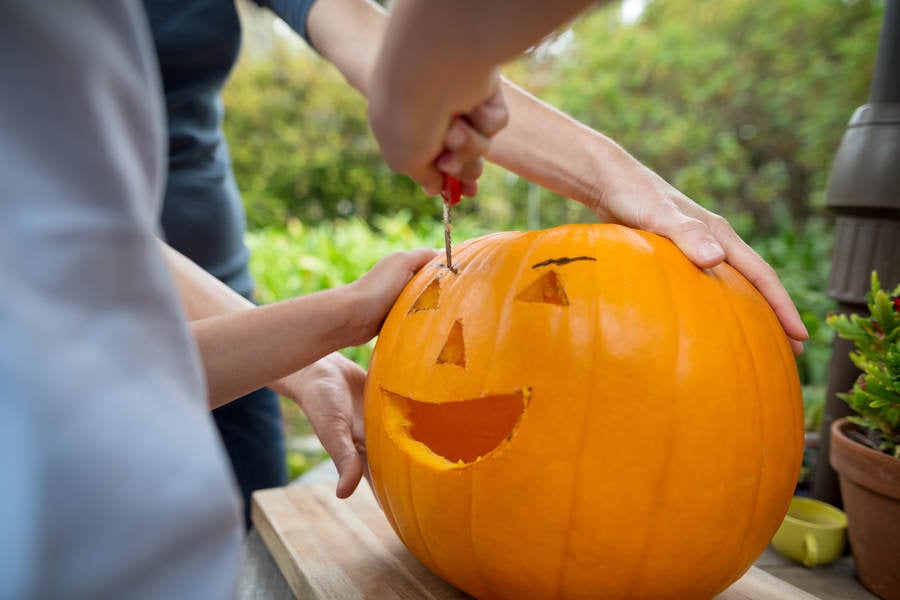 Close-Up View of a Young Girl Carving a Pumpkin with Her Mom