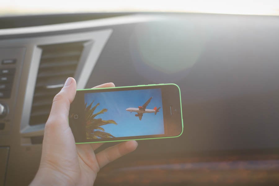 Woman's Hand Holding a Cell Phone in a Car with a Picture of an Aircraft