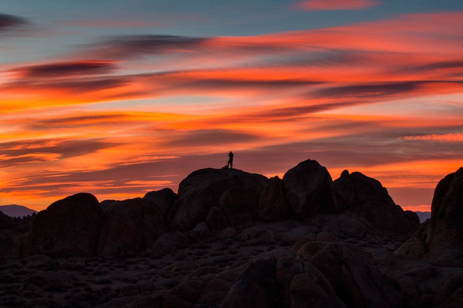 Silhouette of a Photographer Standing on Rocks During a Sunrise