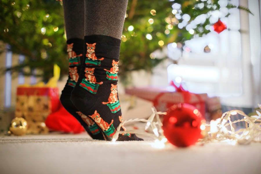 Girl on Her Toes Wearing Christmas Socks Reaching for a Tree Ornament