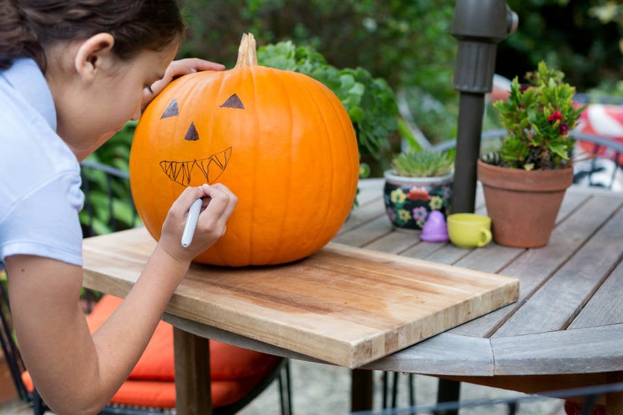 Young Girl Drawing on a Pumpkin Prior Carving It