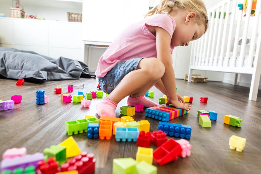 Low-Angle View of a Child Playing with Plastic Blocks on a Floor