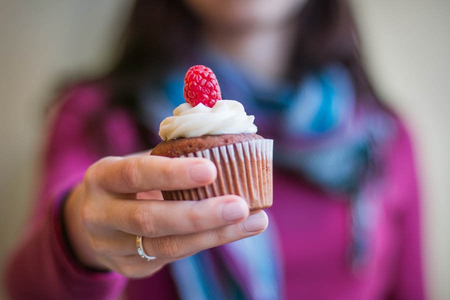 Frontal View of a Woman Holding a Raspberry Cupcake in Her Hand