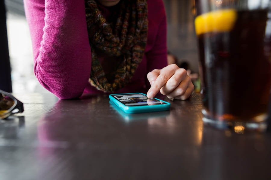 Low-Angle View of a Woman Using a Cell Phone in a Pub