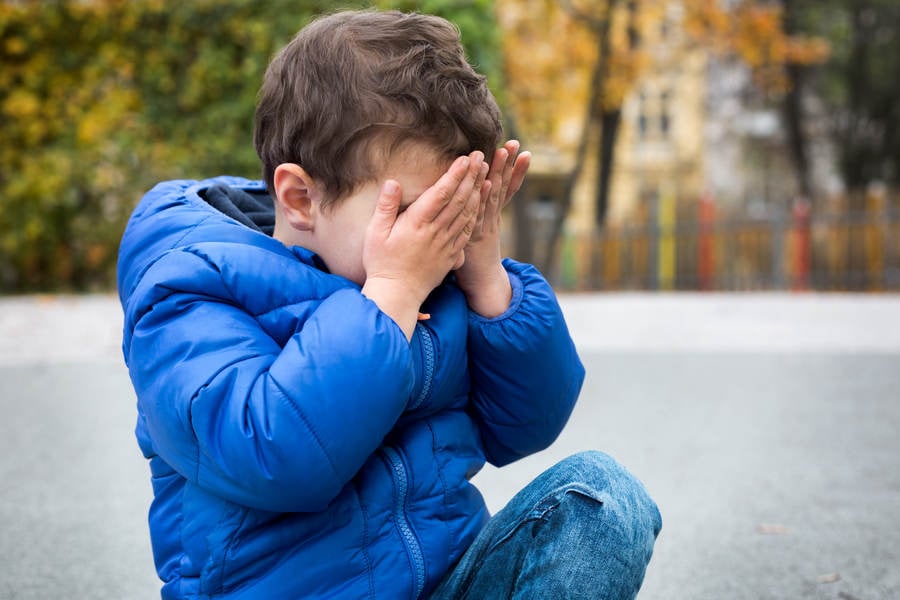  Little Boy Sitting on the Ground at a Playground and Crying
