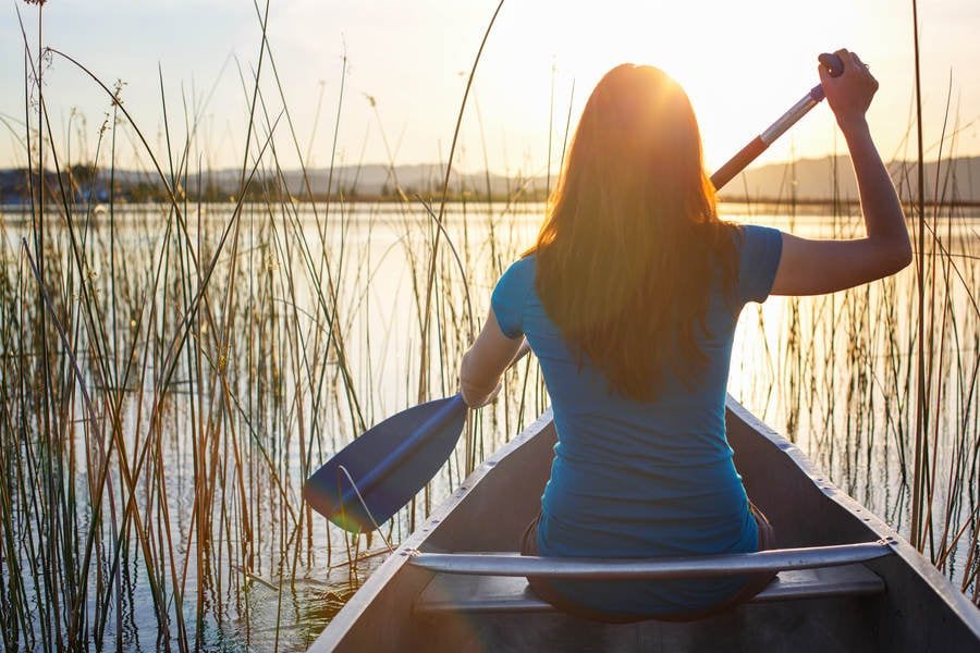 Woman in a Canoe Paddling on a Lake During Sunset