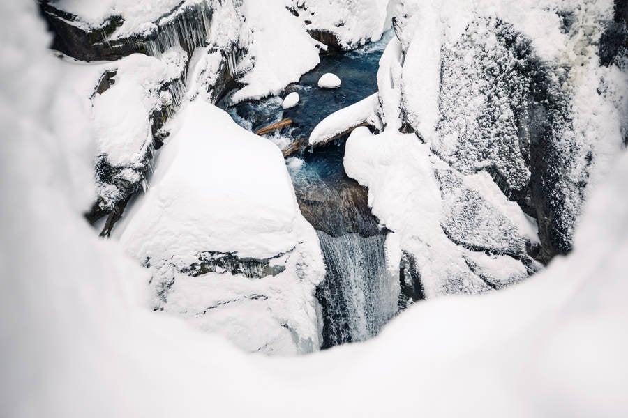 Overhead View of a Winter Waterfall with Snow-Covered Boulders Around