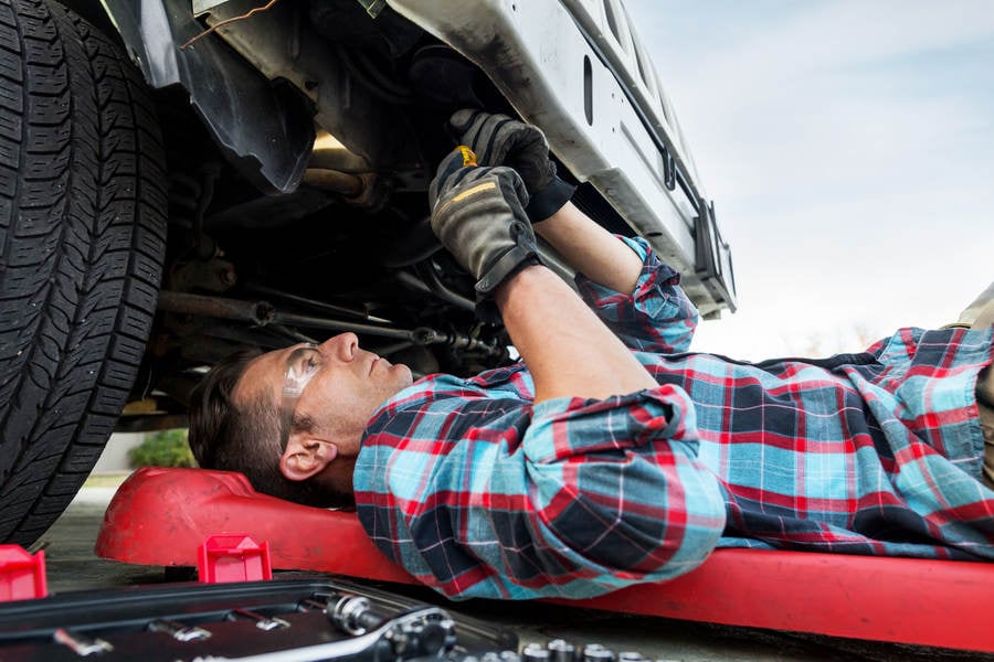 Car Mechanic Working Underneath the Front of a Truck