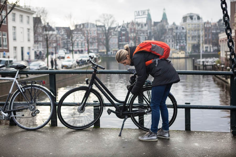 Young Woman Locking a Bicycle on a City Bridge
