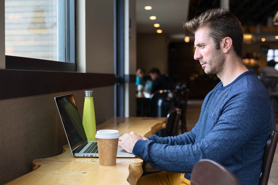Man Working Remotely on a Laptop from a Coffee Shop