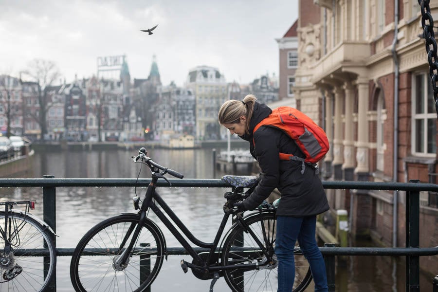 Woman Locking a Bicycle on a City Bridge