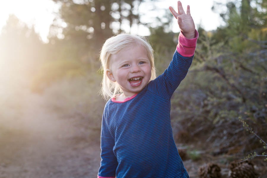 Smiling Toddler Girl Standing on a Trail and Waving