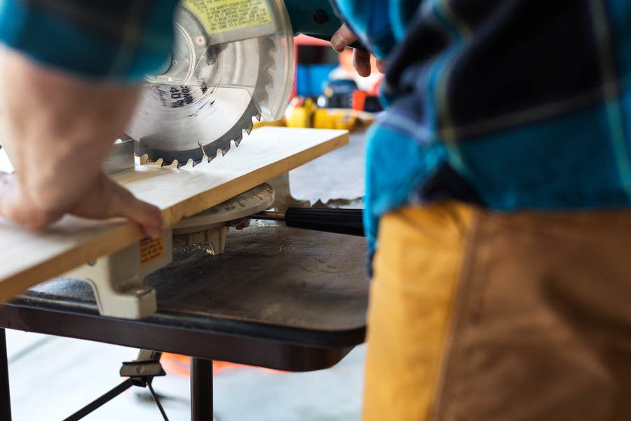 Handyman Cutting a Wooden Board with a Miter Saw