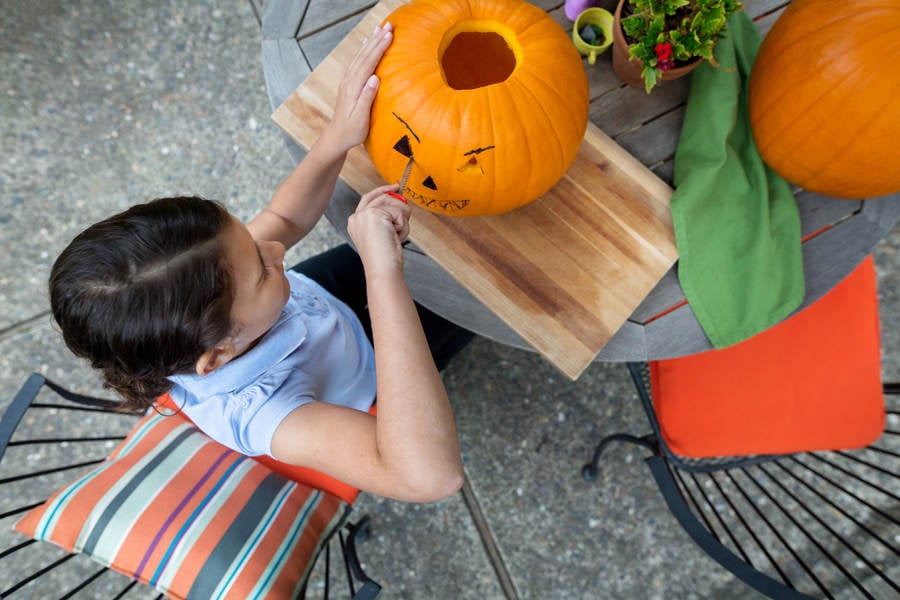 Overhead View of a Young Girl Carving a Pumpkin