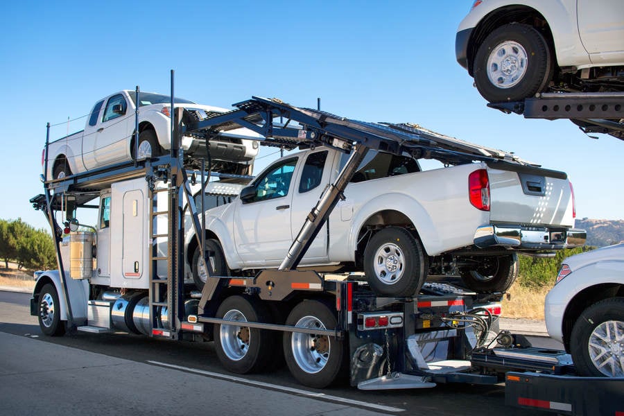 White Pickup Trucks Being Transported on a Trailer Through Highway